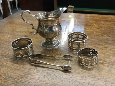 Lot 687 - Georgian silver cream jug, pair of silver sugar tongs, and three silver napkin rings (5 items), all at 4.5oz