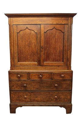 Lot 1263 - George III oak house keeper's cupboard with shelved interior enclosed by two gothic panelled doors, the base with three short and two long graduated drawers with cock beaded edge and turned bun han...