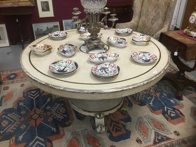 Lot 1285 - Antique cream painted circular breakfast table, with oval tilt top on bulbous faceted column and castors 143cm diameter