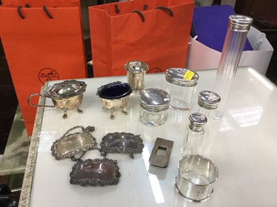 Lot 725 - Silver napkin ring, three silver spirit labels, silver three piece cruet set, silver money clip and five silver topped glass pots