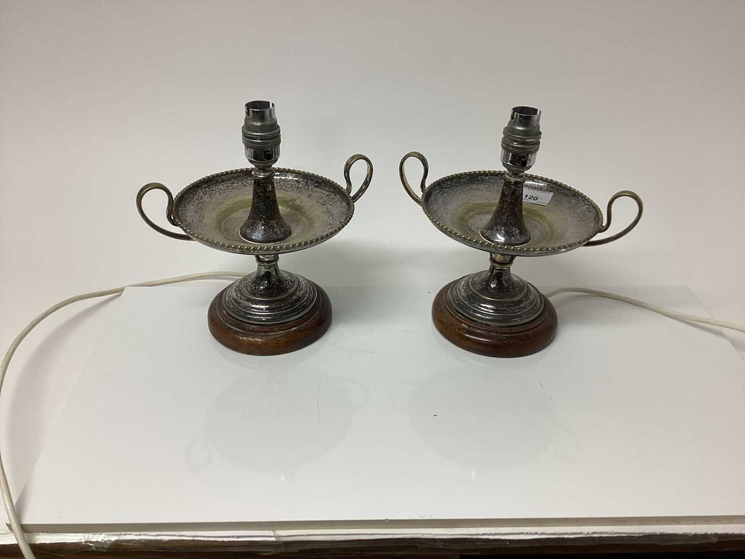 Lot 120 - Pair of silver plated table lamps with twin handles and gadrooned borders, on wooden bases