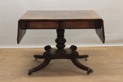 Lot 1308 - Regency rosewood sofa table, rectangular drop leaf top with canted angles, with single drawer to end reel moulded frieze, on bulbous column and hipped reeded quatrefoil supports terminating in bras...