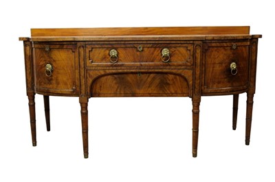 Lot 1310 - Good George III mahogany bowfront sideboard, with rear shelf and central frieze drawer and flanking cupboards, one with fitted cellarette, each with lion mask handles, raised on fluted tapered legs...