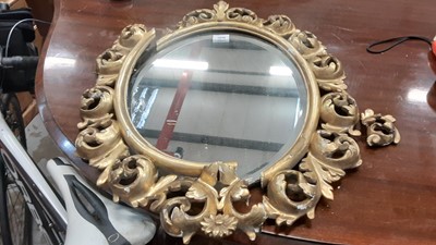 Lot 1034 - Oval bevelled wall mirror in ornate gilt frame, 66cm high, 52cm wide