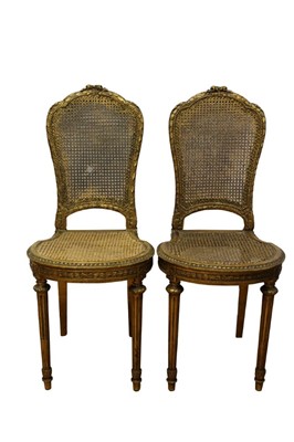 Lot 1380 - Pair of Louis XVI style gilt and caned side chairs, raised on fluted tapered legs