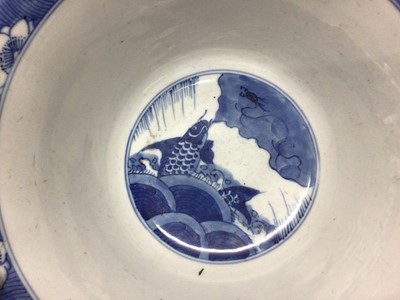 Lot 129 - Fine Chinese blue and white bowl, Kangxi period, of round form with straight foot and flared rim, decorated with dragons chasing flaming pearls, amongst stylised clouds and waves, prunus flowers on...