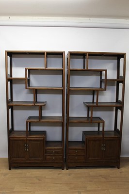 Lot 1414 - Pair of Chinese hardwood floor standing cabinets, with asymmetric arrangement of open shelves and cupboards on stiles, 88cm wide x 32cm deep x 190cm high