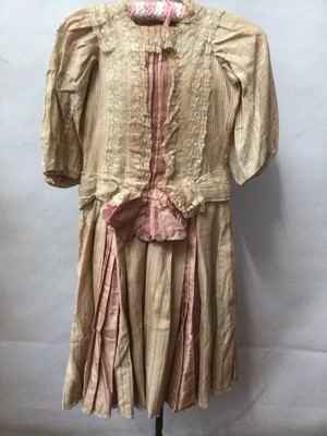 Lot 2152 - Early 20th century girl's dress.  Inset with pink satin silk and trimmed with embroidered net lace.  Brass hook fastenings.  Similar dress with ruched and pleated satin silk and floral woven silk a...