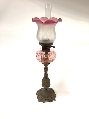 Lot 2559 - Brass oil lamp with cranberry tinted shade