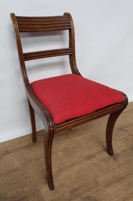 Lot 1466 - Set of twelve Regency mahogany dining chairs with reeded bar backs, drop-in seats, on sabre legs (one a copy)