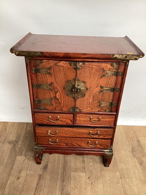 Lot 1028 - Chinese elm miniature cabinet with brass mounts, the twin cupboard doors above two short and two long drawers, on shaped supports