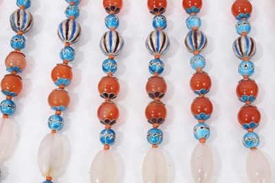 Lot 87 - Nine Chinese carnelian bead necklaces interspaced with enamelled beads and pink hard stones, all with silver wire work clasps