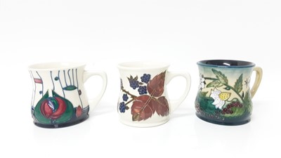 Lot 1230 - Three Moorcroft pottery mugs to include Macintosh design, signed Rachel Bishop, dated 23.3.97, Bramble pattern and one decorated with bee and butterfly, dated 99, all boxed