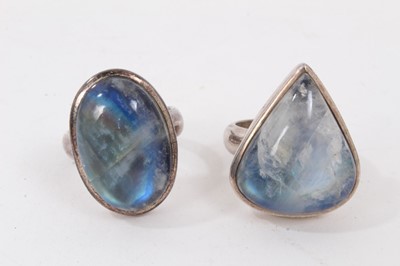 Lot 230 - Two silver abstract design rings, one set with a rainbow moonstone cabochon and one with black star diopside cabochon, together with two other silver large rainbow moonstone rings (4)