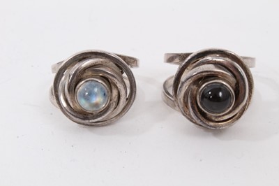Lot 230 - Two silver abstract design rings, one set with a rainbow moonstone cabochon and one with black star diopside cabochon, together with two other silver large rainbow moonstone rings (4)