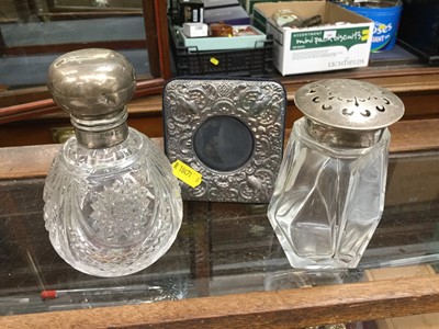 Lot 704 - Edwardian silver topped cut glass scent bottle, silver topped sugar castor and a silver mounted photograph frame (3)