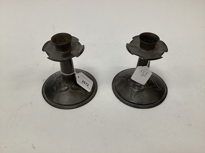 Lot 2672 - A pair of Art Nouveau Tudric pewter candlesticks designed by Archibald Knox for Liberty, scalloped drip pans, tapering stems and circular domed foot with stylised flower decoration, stamped marks,...