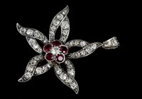 Lot 756 - Ruby and diamond flower pendant with a central...