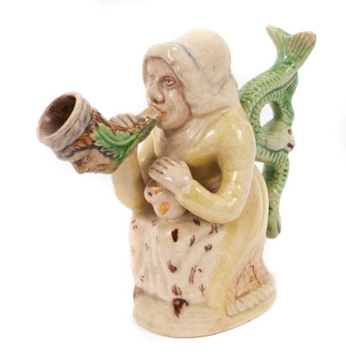 Lot 19 - Prattware figure, circa 1810, in the form of Martha Gunn smoking a large pipe, with a serpent form handle and cat on her lap, decorated in typical Prat colours, 11.5cm high