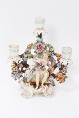 Lot 26 - Pair of Sitzendorf porcelain three-branch figural candelabra, polychrome painted on scrollwork feet, 25cm high
