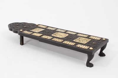 Lot 225 - 19th century Chinese black hardwood cribbage board, with carved floral decoration, inlaid ivory markers and carved plaques with Chinese scenes, slide covered peg box with four pegs, on four carved...