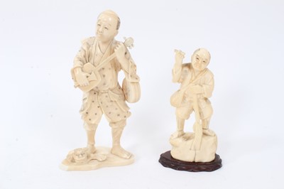 Lot 737 - Late 19th century Japanese carved ivory figure of a musician with temple dog mask at feet, signed and another figure of a huntsman with musket (2)