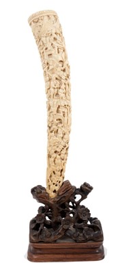 Lot 739 - Late 19th century Chinese carved ivory tusk ornately decorated with figures, buildings and flora on original carved hardwood stand decorated with flowers 45 cm high