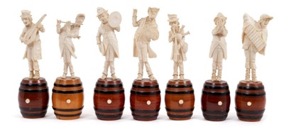 Lot 762 - Set of seven 19th century Dieppe carved ivory figures of musicians, each humorously carved standing on a wooden barrel, 16cm high