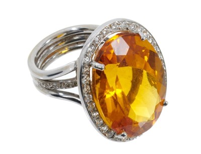 Lot 439 - Citrine and diamond cluster ring with a large oval mixed cut citrine measuring approximately 25mm x 18mm x 12.5mm surrounded by a border of 32 brilliant cut diamonds, with further diamonds to the s...