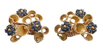 Lot 486 - Pair of 1970s sapphire and gold earrings, each with three clusters of blue sapphires in textured gold setting of organic abstract form, stamped K18, approximately 28mm.