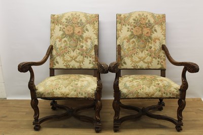 Lot 1035 - Pair of Carolean style carved walnut open armchairs, with arched pad back and seat and scrolled arms, raised on cabriole legs united by wavy stretchers