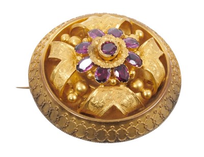 Lot 470 - Victorian gold and garnet target brooch of circular form with a central flower head cluster, textured gold scrolls and applied gold filigree, 43mm diameter.
