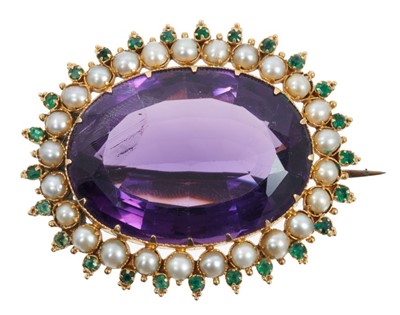 Lot 469 - Victorian amethyst seed pearl and emerald brooch with a large oval mixed cut amethyst surrounded by a border of half pearls and emeralds in gold setting, 46mm.