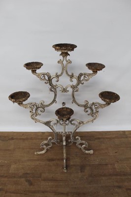 Lot 1474 - Antique cast iron plant stand, with six dished holders (one missing) issuing from scrolled frame on scrolling splayed supports, 92cm wide x 108cm high