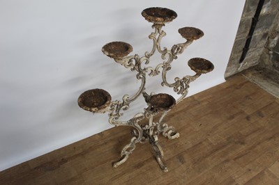 Lot 1474 - Antique cast iron plant stand, with six dished holders (one missing) issuing from scrolled frame on scrolling splayed supports, 92cm wide x 108cm high