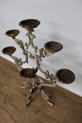 Lot 1474 - Antique cast iron plant stand, with six dished holders (one missing) issuing from scrolled frame on scrolling splayed supports, 92cm wide x 108cm high