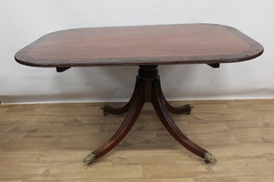 Lot 1517 - Regency mahogany and rosewood crossbanded breakfast table, with rounded rectangular hinged top on turned column and swept reeded quadruped supports, terminating in unusual brass lion mask terminals...