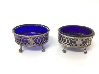 Lot 27 - Pair of Georgian silver salt cellars of oval form with blue glass liners, on claw and ball feet (marks rubbed).