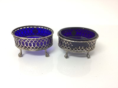 Lot 27 - Pair of Georgian silver salt cellars of oval form with blue glass liners, on claw and ball feet (marks rubbed).