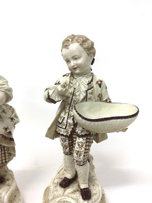 Lot 8 - Pair of continental porcelain figures of a boy and girl, shown holding baskets, on scrollwork bases, with gilt and enamelled decoration, marked to bases, 29cm high