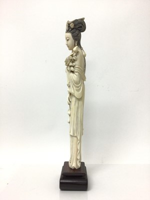 Lot 13 - Large 19th century Japanese ivory tusk figure of a woman, shown wearing a long robe and holding flowers, on a wooden base, total height 46cm