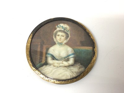 Lot 29 - Georgian portrait miniature on ivory of a young woman, shown seated with her arms crossed, in gilt frame, 8cm diameter
