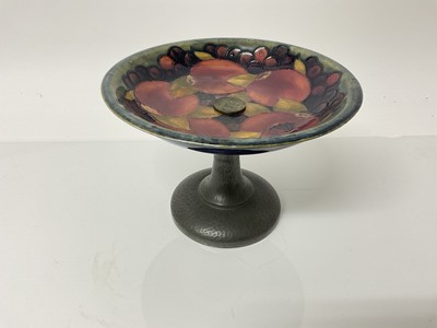 Lot 1039 - Moorcroft pottery tazza decorated in the pomegranate pattern on blue and green ground, on Tudric pewter base, impressed marks and blue painted signature, 13cm high, 19cm diameter