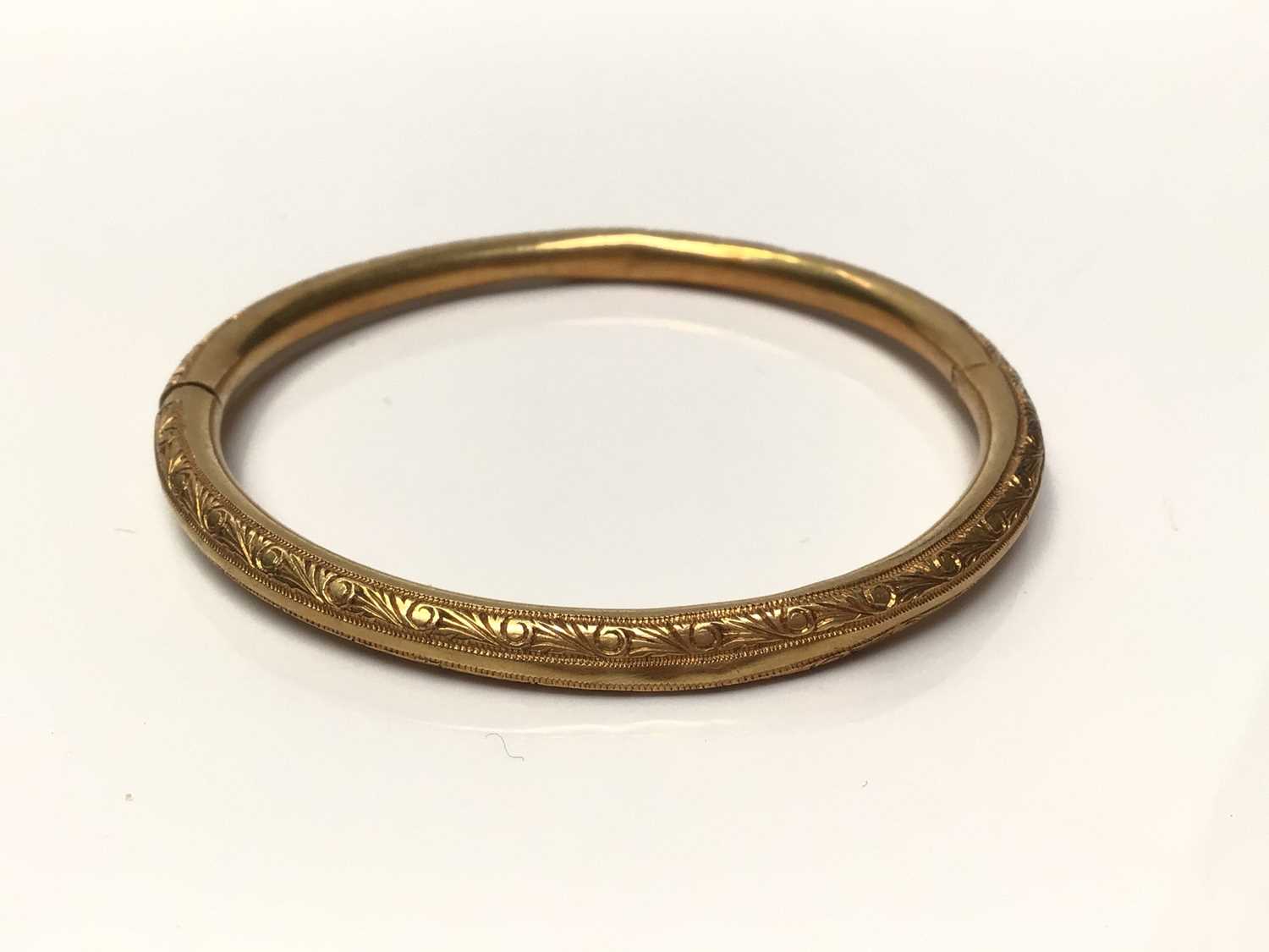 Lot 113 - Yellow metal bangle with engraved scroll decoration