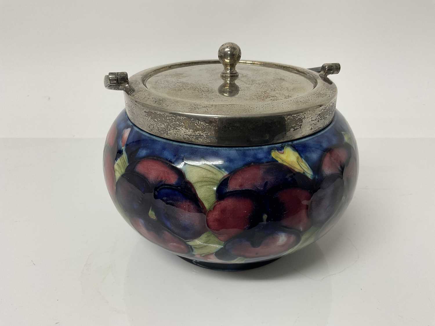 Lot 1109 - Moorcroft pottery biscuit barrel decorated in the pansy pattern with plated lid, impressed marks and green painted signature to base, 12cm high excluding handle