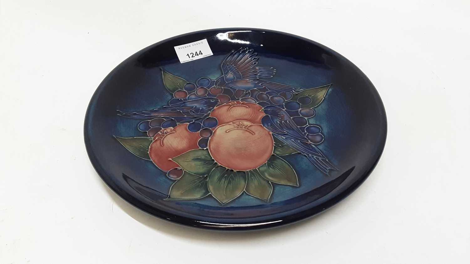 Lot 1244 - Moorcroft pottery plate decorated in the fruit and finch pattern on blue ground, impressed marks and painted WM, 26cm diameter