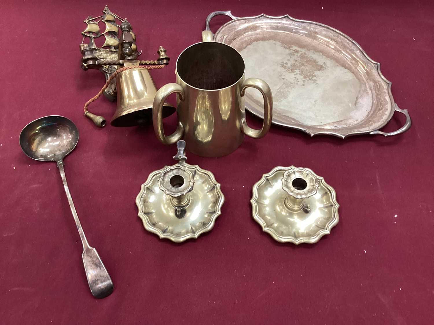 Lot 2642 - Collection of silver plated ware to include Tyg engraved 'U.C.S. Bicycle Race', pair of chamber sticks and cutlery sets together with a brass bell (1 box)