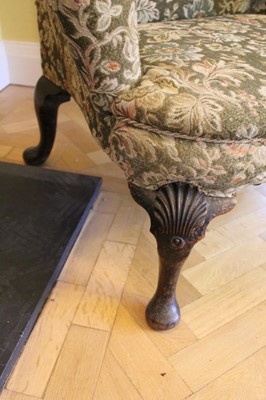 Lot 1212 - Good George I walnut wing back armchair with scroll arms on carved cabriole front supports with carved shell knees terminating on fad feet.