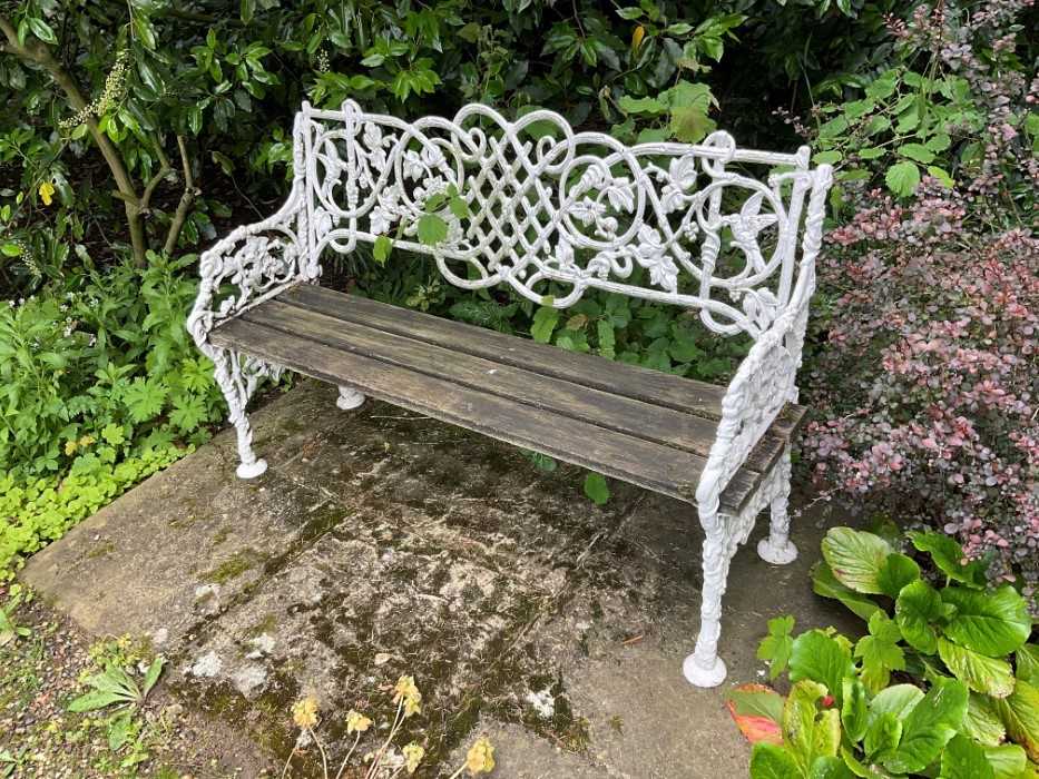 Lot 1277 - White painted cast iron bench, with lattice, vine and bird ornament