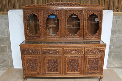 Lot 205 - Highly ornate Anglo-Indian carved hardwood suite of dining furniture, comprising rounded rectangular dining table on trestle base, 205 x 123cm, set of six high back chairs and sideboard with glazed...